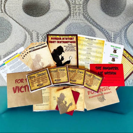 A collection of printed cards, labels, and small signs arranged on a teal surface in front of a gray and white patterned wallpaper background. The items include a brown paper card reading 'FOR VICTIM', several tan and yellow informational cards, a red card reading 'THE ANSWERS ARE WITHIN', and other printed materials with text and silhouettes.