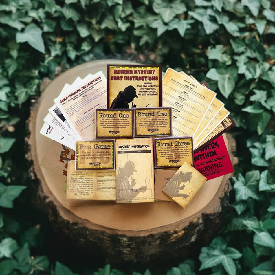 A tabletop game set displayed on a cut tree stump surrounded by green ivy. The set includes multiple cards, instruction sheets, and boxes with vintage-style aged paper designs and illustrated cover art.