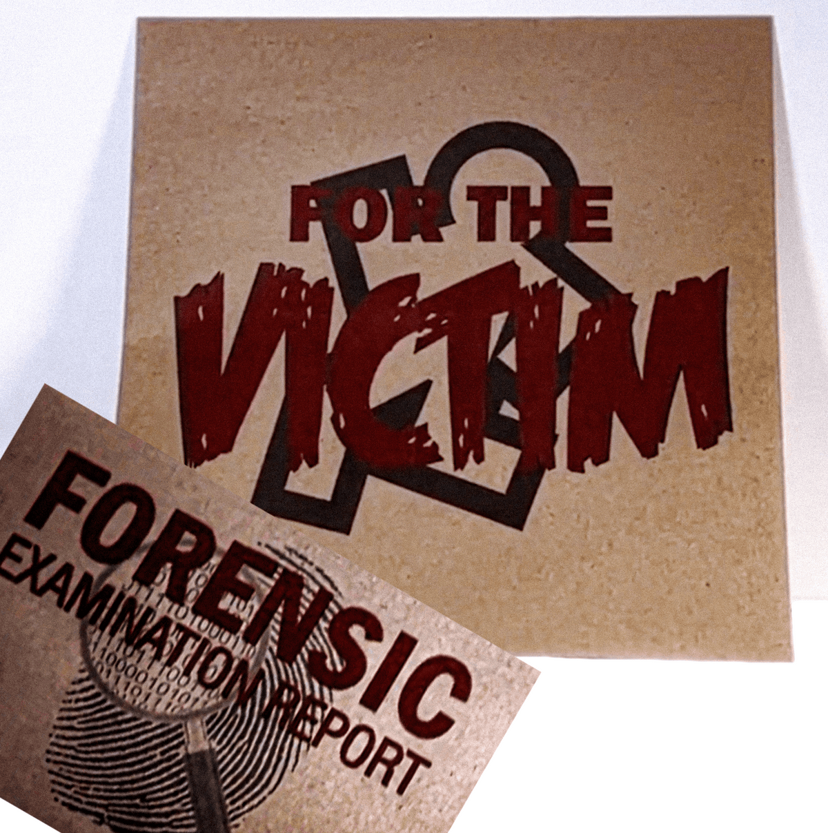A square kraft-paper style print or card with the words 'FOR THE VICTIM' in large distressed red lettering over a black ampersand graphic, with a second matching print partially visible in front reading 'FORENSIC EXAMINATION REPORT.'.