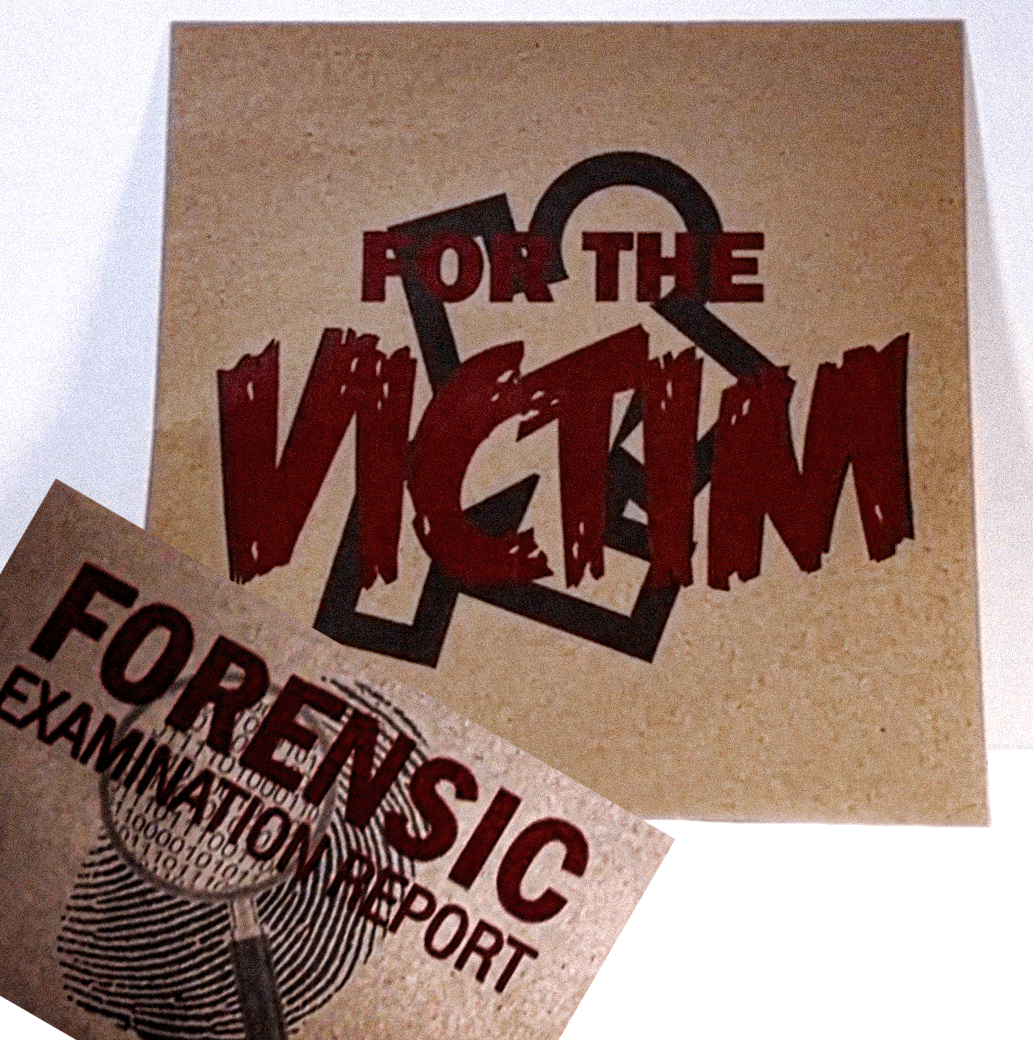 A square kraft-paper style print or card with the words 'FOR THE VICTIM' in large distressed red lettering over a black ampersand graphic, with a second matching print partially visible in front reading 'FORENSIC EXAMINATION REPORT.'.