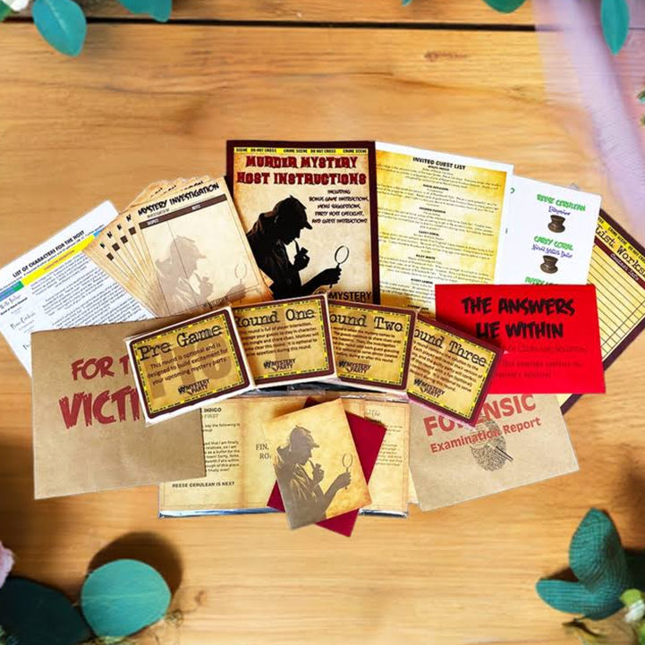 A styled flat-lay of a mock 'Anger Ativity Root Instruction' booklet and various printed cards, pamphlets, and envelopes arranged on a wooden tabletop, surrounded by decorative flowers and greenery.
